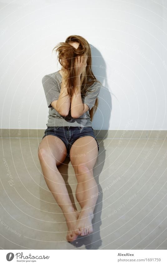 Young athletic long legged woman sits barefoot against the wall with her long hair covering her face Athletic Fitness Young woman Youth (Young adults) Legs Feet