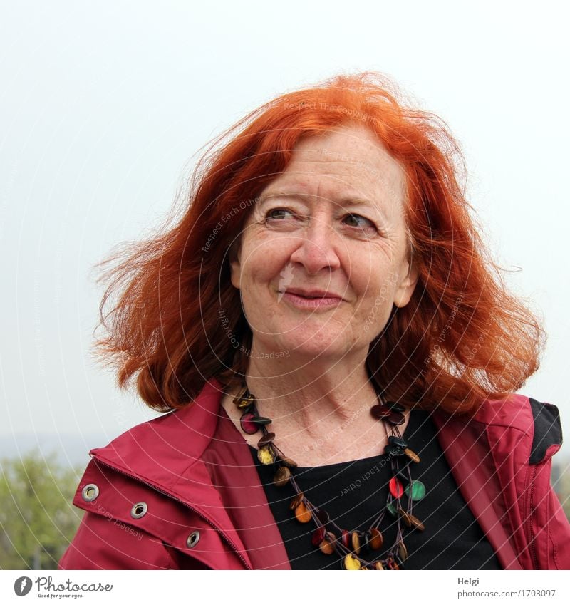 Portrait of an elderly woman with long red hair, looking mischievously to the side, with red jacket, black shirt and colourful necklace Human being Feminine