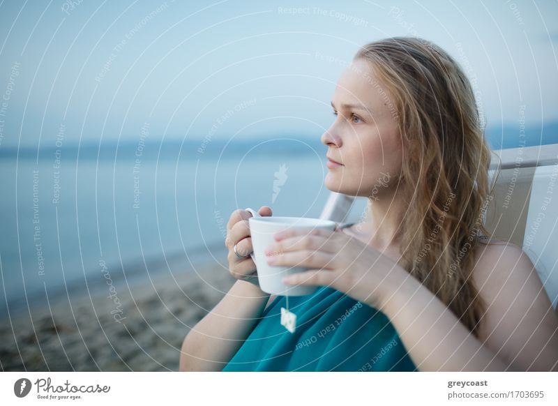 Woman enjoying a cup of tea at the seaside sitting relaxing on a deckchair with a blissful expression overlooking a tropical beach Beverage Drinking Coffee Tea