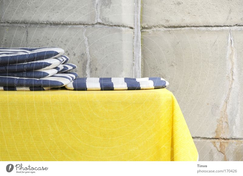 blue-white seat cushions on yellow tablecloth in front of concrete wall Colour photo Multicoloured Exterior shot Close-up Copy Space bottom Day Table Blue