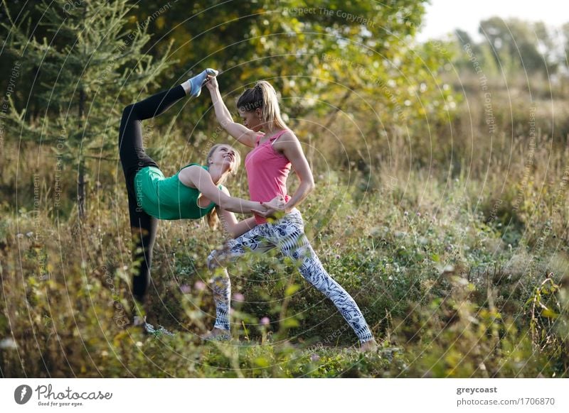 Two beautiful young female gymnasts or dancers working out in the countryside on a rural track stretching in an elegant graceful pose Elegant Happy Beautiful