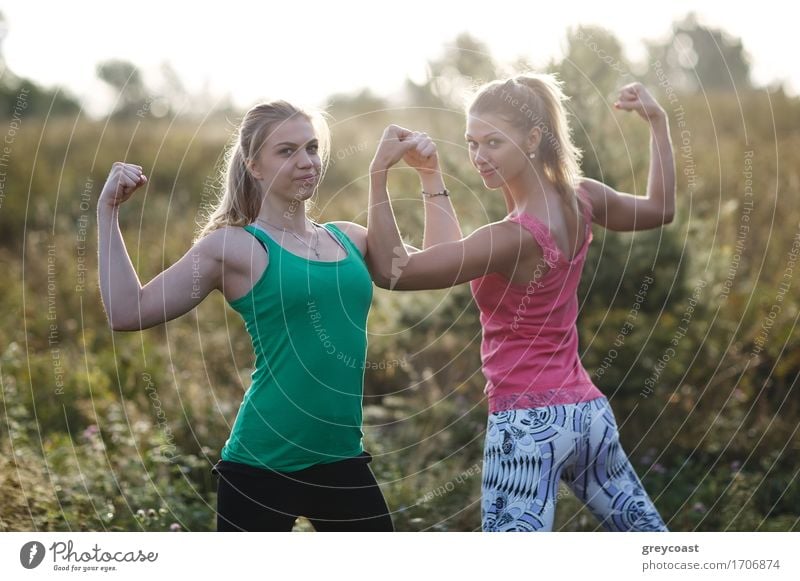 Two athletic young standing outdoors girls flexing their arm muscles during a workout in the garden Summer Garden Sports Girl Young woman Youth (Young adults)