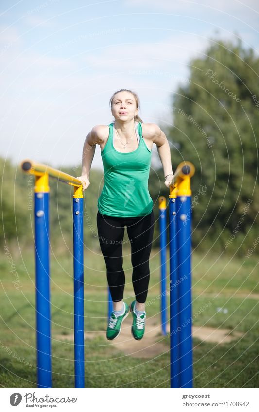Attractive fit young woman gymnast exercising outdoors on parallel bars during a training workout Sports Fitness Sports Training Young woman