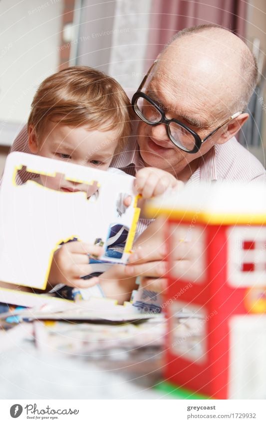 Grandfather helping his little grandson to solve puzzle. Happy family time Joy Leisure and hobbies Playing Child Human being Boy (child) Man Adults