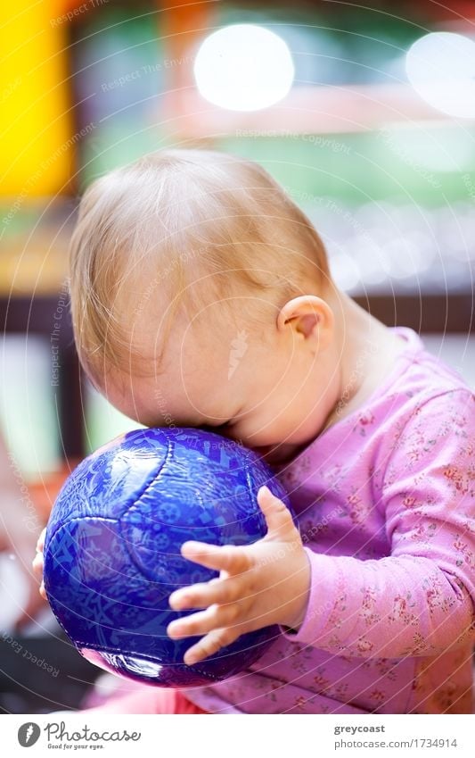 Cute little baby playing with a big blue ball sitting with its face pressed up against the ball, side view Joy Playing Summer Child Baby Girl Infancy 1