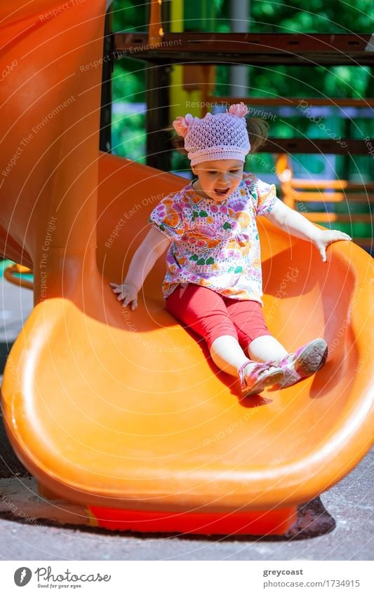 Small girl at the playground having fun on a slide - a Royalty
