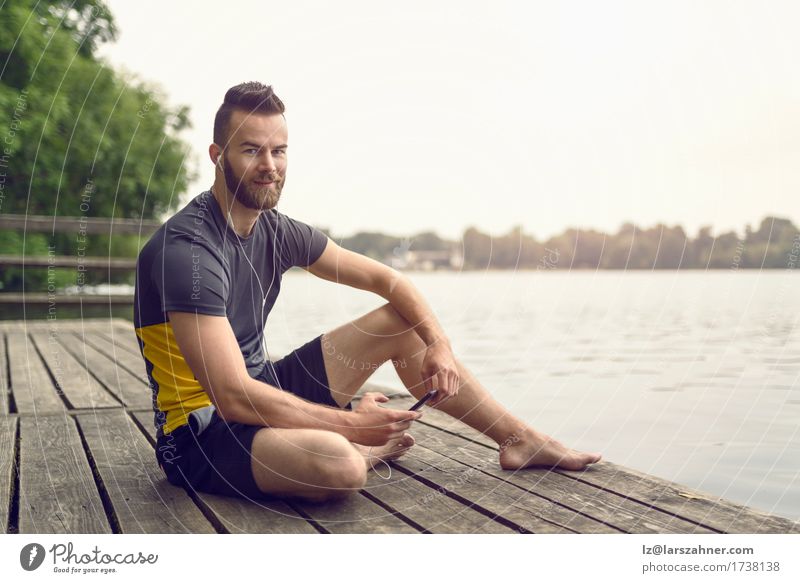 Attractive bearded young man relaxing on a wooden deck Lifestyle Face Relaxation Music Telephone PDA Man Adults 1 Human being 18 - 30 years Youth (Young adults)