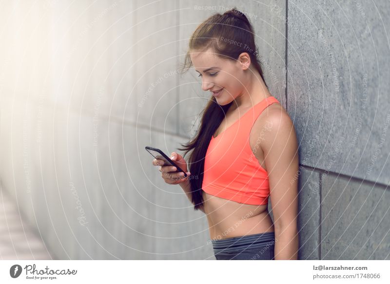 Sporty young woman checking her mobile Face Summer Telephone PDA Woman Adults 1 Human being 18 - 30 years Youth (Young adults) Warmth Brunette Fitness Smiling