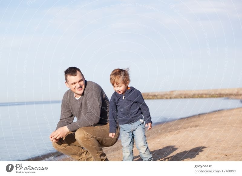 Smiling father with his young son at the beach crouching down on the sand with a smile as the boy stands alongside him Joy Happy Beach Ocean Boy (child) Father