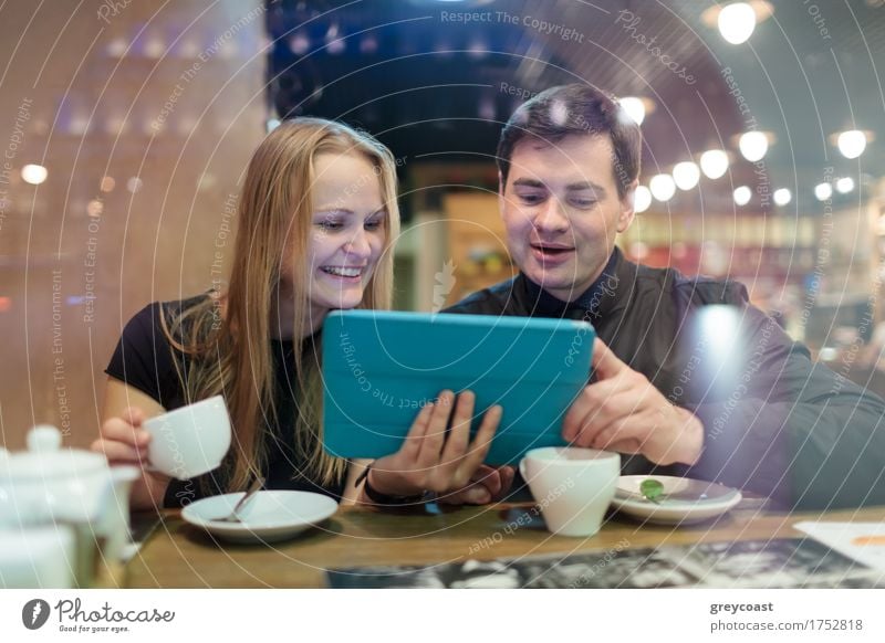 Happy young man and woman drinking coffee while looking on tablet Coffee Tea Restaurant Meeting Computer Young woman Youth (Young adults) Young man