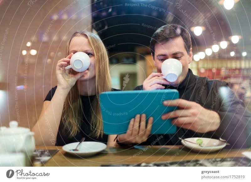 Man and woman drinking coffee while holding a smart tablet Coffee Tea Restaurant Meeting Computer Young woman Youth (Young adults) Young man Couple 2