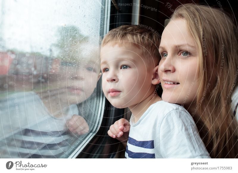 Mother and son looking through a train window as they enjoy a days travel with the small boys face reflected in the glass Vacation & Travel Trip Child