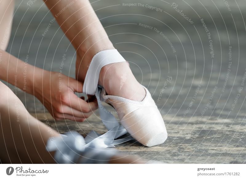 Close-up shot of a ballerina taking off the ballet shoes sitting on the floor in the studio Elegant Beautiful Academic studies Dancing school Girl