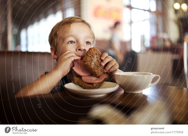 Little boy in a cafe during lunch. Hungry kid eating sausage from his sandwich Sausage Bread Breakfast Lunch Dinner Tea Child Boy (child) 1 Human being Blonde
