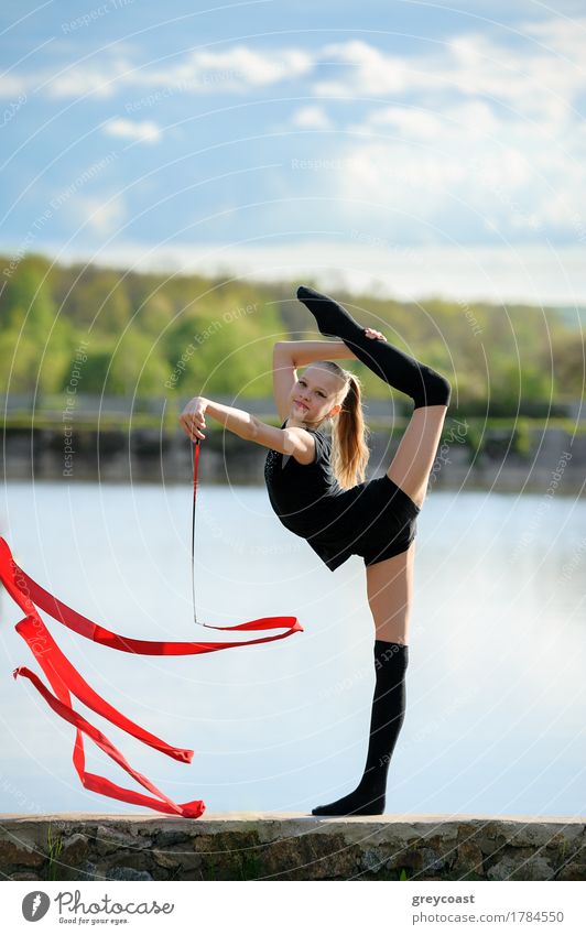 Teen rhythmic gymnast is holding leg in vertical split doing ribbon exercises. Body Summer Garden Sports Fitness Sports Training Human being Feminine Girl Woman
