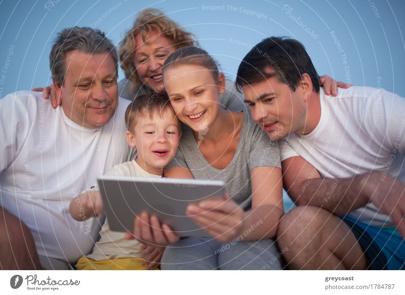 Happy big family having good time together. Grandparents and parents looking at the pad screen while boy using it Joy Leisure and hobbies Playing