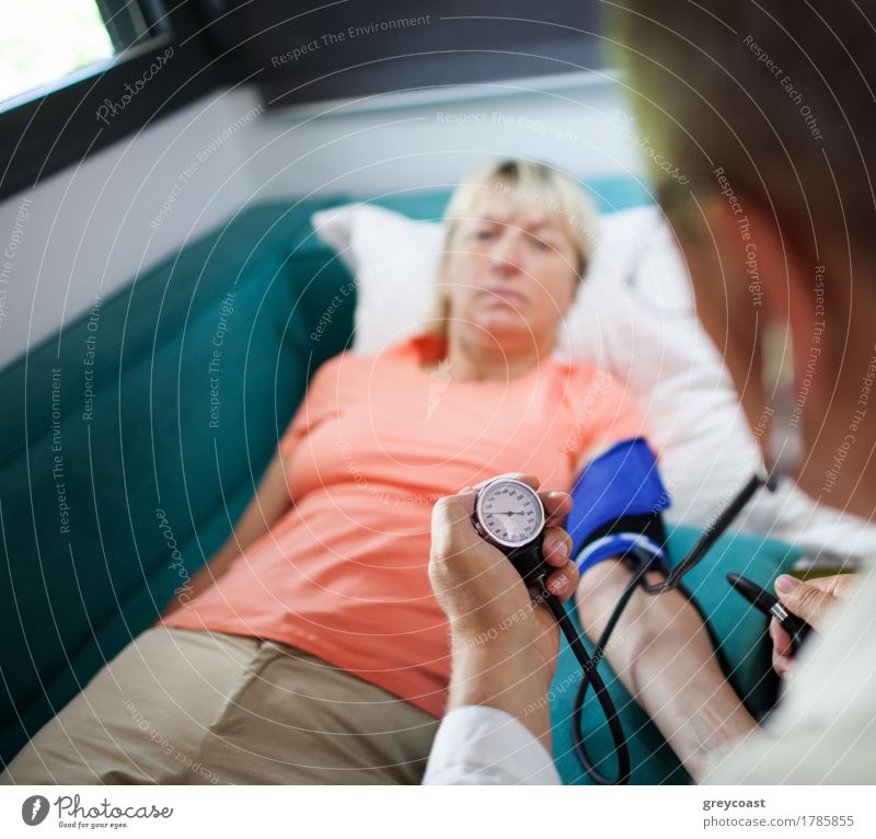 Doctor checking blood pressure of a woman patient during the visit at home. Focus on manometer Health care Illness Medication Flat (apartment) Sofa