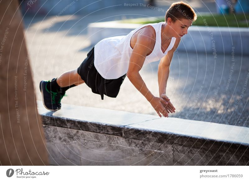 Young sportive man doing push-ups on border stone in the city. Urban exercising and training Lifestyle Body Sports Young man Youth (Young adults) Adults Hand 1