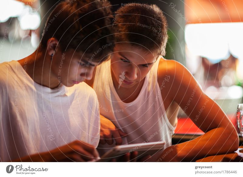 Two male teenagers browsing the internet in cafe. Entertaining with electronics Leisure and hobbies Computer Internet Human being Man Adults Friendship