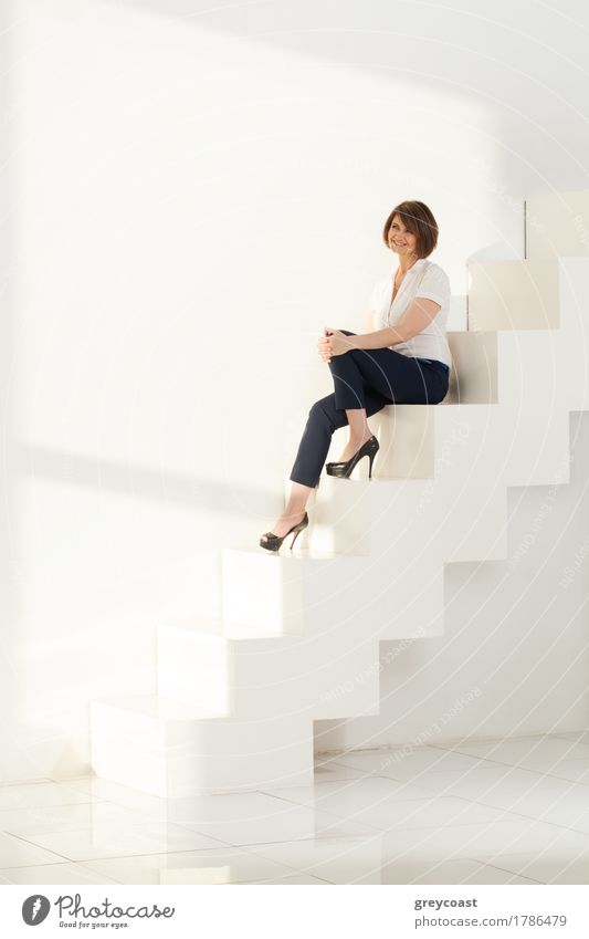 Smiling businesswoman sitting on steps of modern ladder Elegant Style Design Beautiful Calm Office Business Ladder Human being Woman Adults 1 High heels