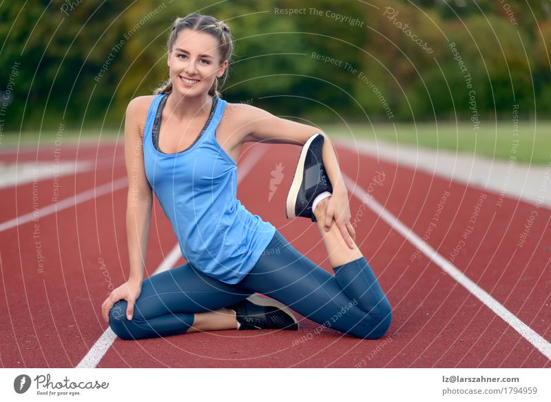 Happy fit young woman doing stretching exercises - a Royalty Free