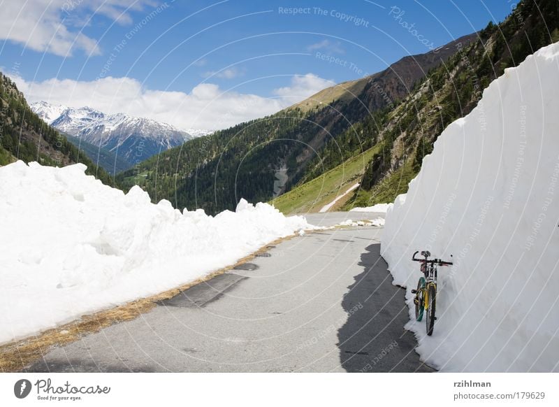 Snow wall at the Umbrail Pass Colour photo Exterior shot Copy Space left Day Sunlight Mountain Bicycle Clouds Hill Rock Alps Lanes & trails Driving Blue Gray