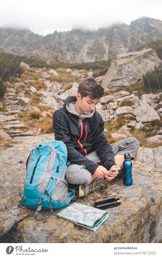 Boy resting on a rock and charging a mobile phone Bottle Lifestyle Leisure and hobbies Vacation & Travel Adventure Freedom Summer Mountain Hiking Human being