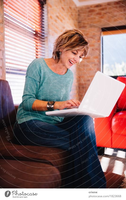 Mature woman video chatting friend with laptop on couch Lifestyle Joy House (Residential Structure) Work and employment Office Business Computer Notebook