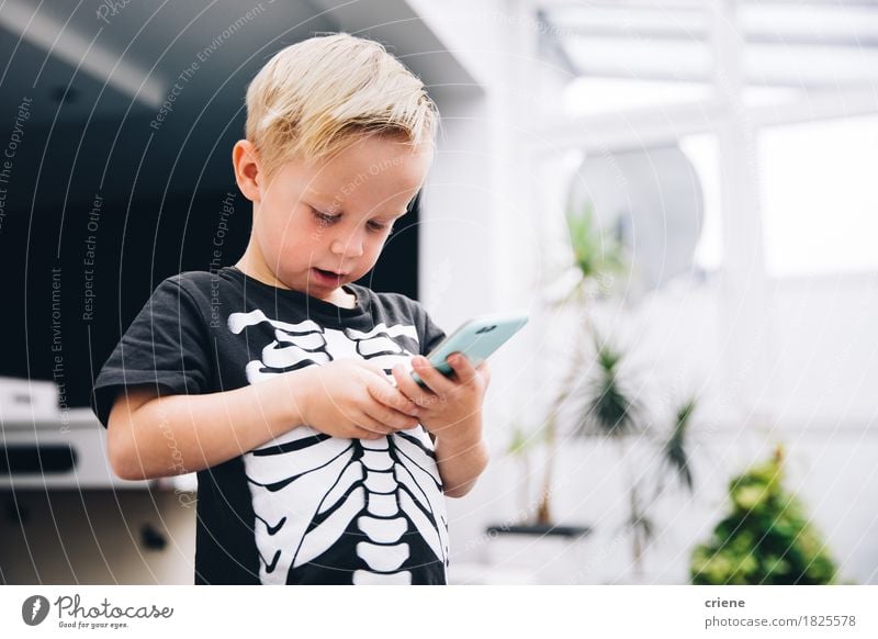 Little boy in skeleton shirt playing games on smart phone Lifestyle Joy Playing Telephone Cellphone PDA Technology Entertainment electronics Internet