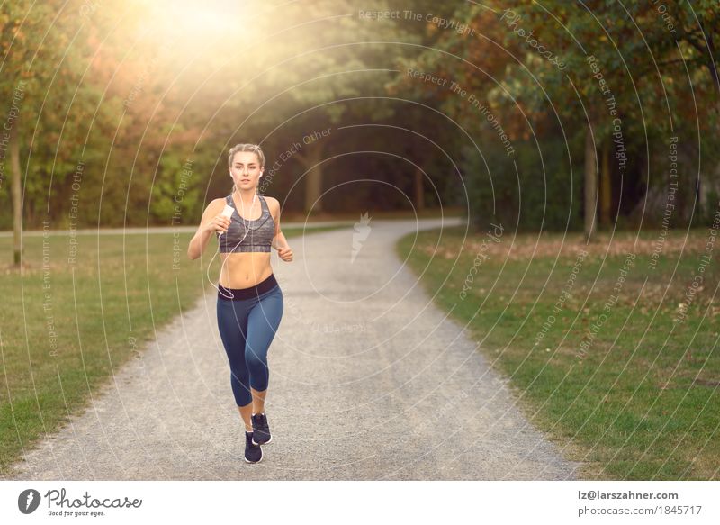 Woman jogging along a country road while listening to music Lifestyle Happy Summer Music Sports Jogging PDA Feminine Adults 1 Human being 18 - 30 years