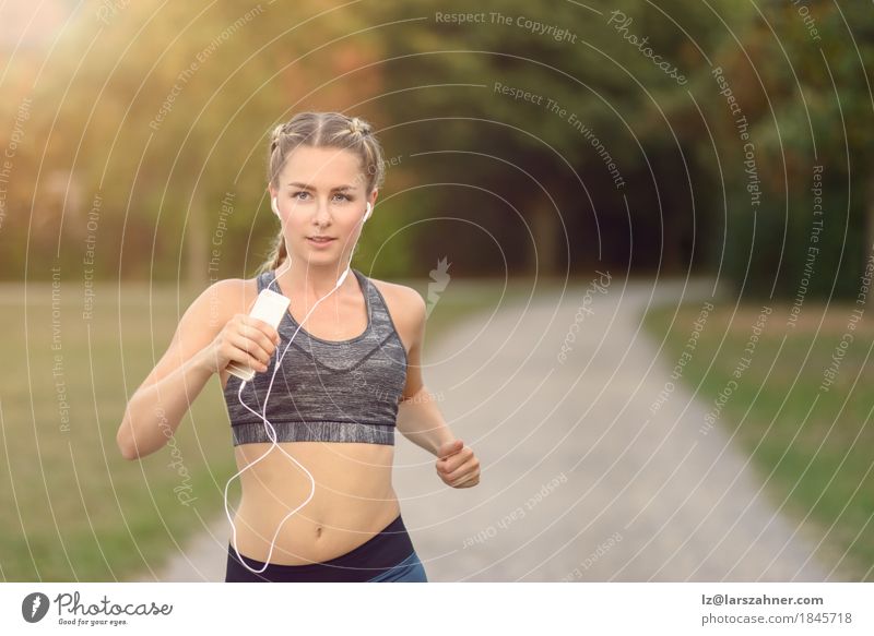 Woman jogging along a country road while listening to music Lifestyle Summer Music Sports Jogging PDA Feminine Adults 1 Human being 18 - 30 years