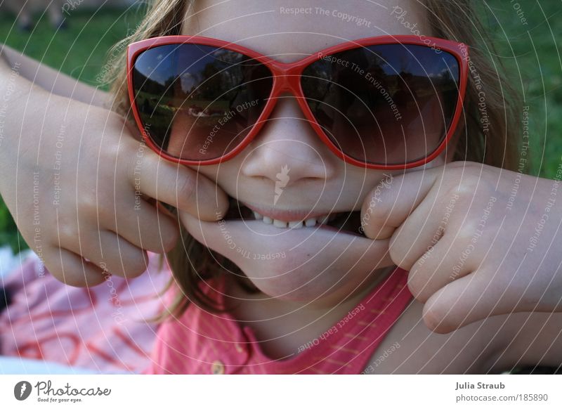 Show me your teeth. Human being Feminine Child Girl Infancy 1 Nature Summer Beautiful weather Grass Meadow T-shirt Sunglasses Brunette Short-haired Smiling Sit