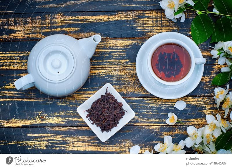 Black tea in a white cup and saucer and jasmine flowers Herbs and spices Breakfast Tea Table Plant Flower Leaf Wood Fresh Hot Brown Yellow Green White branch