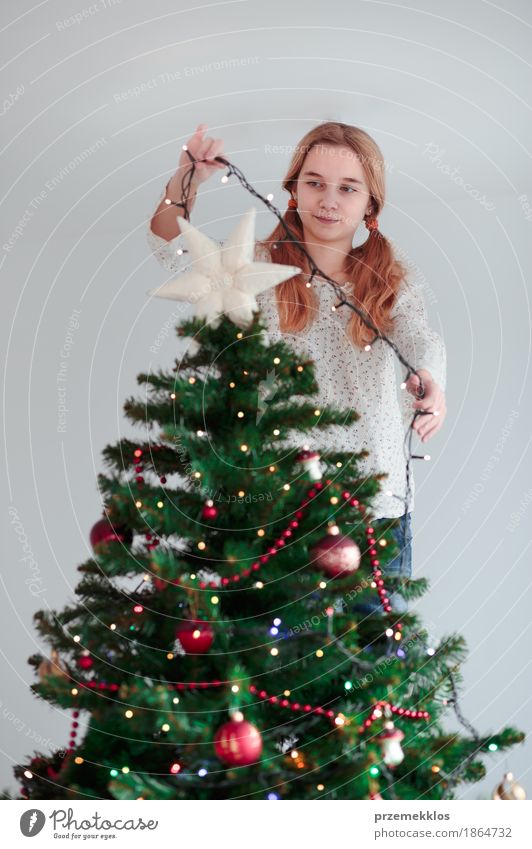Young girl decorating Christmas tree with lights at home Lifestyle Joy Decoration Feasts & Celebrations Christmas & Advent Human being Child Girl 1 8 - 13 years