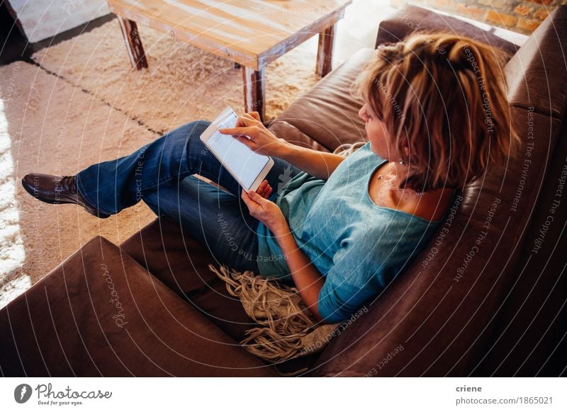 mature woman sitting on sofa using digital tablet Lifestyle Reading House (Residential Structure) Living room Office Business Computer Technology