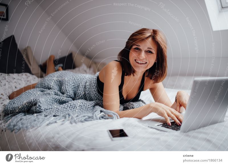 Young caucasian women lying in bed with laptop smiling Lifestyle Joy Beautiful Flat (apartment) Bed Bedroom Entertainment School Study Academic studies