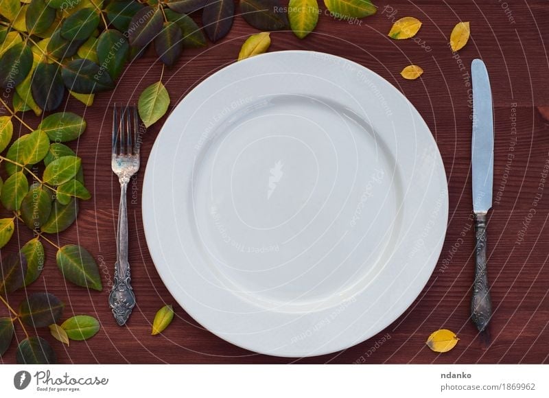 Empty white plate, knife and fork on brown wood surface Lunch Plate Knives Fork Table Kitchen Restaurant Leaf Metal Brown White empty table setting twig ceramic