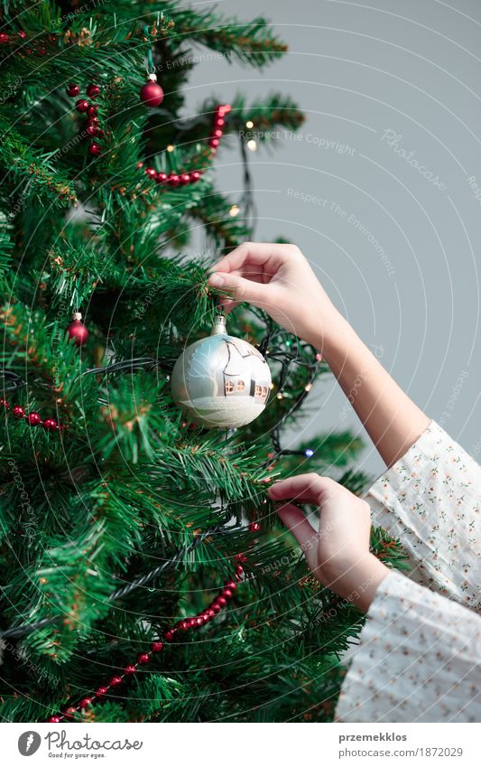 Young girl decorating Christmas tree with ball at home Lifestyle Joy Decoration Feasts & Celebrations Christmas & Advent Human being Girl Arm Hand 1 Tree
