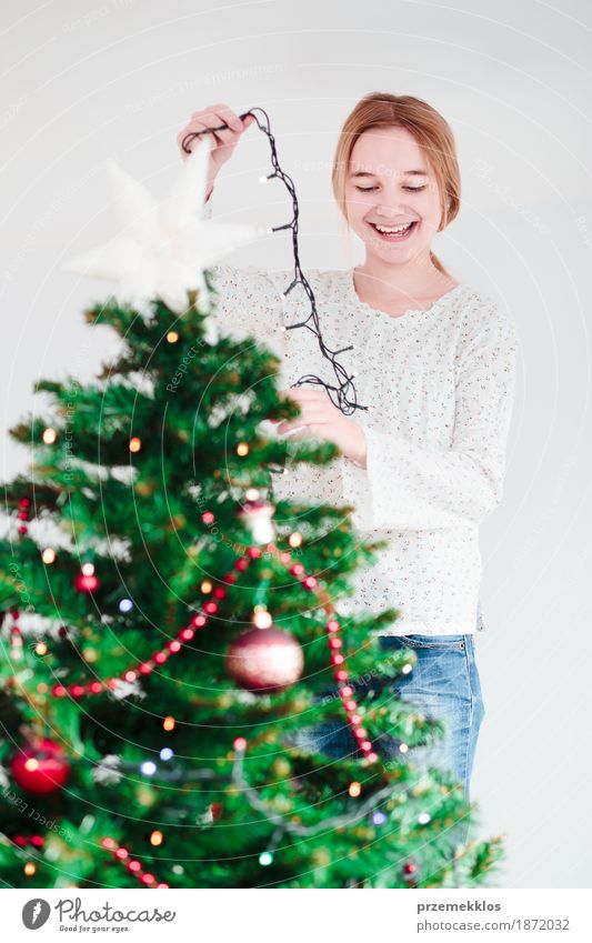 Young girl decorating Christmas tree with lights at home Lifestyle Joy Decoration Feasts & Celebrations Christmas & Advent Human being Girl Youth (Young adults)