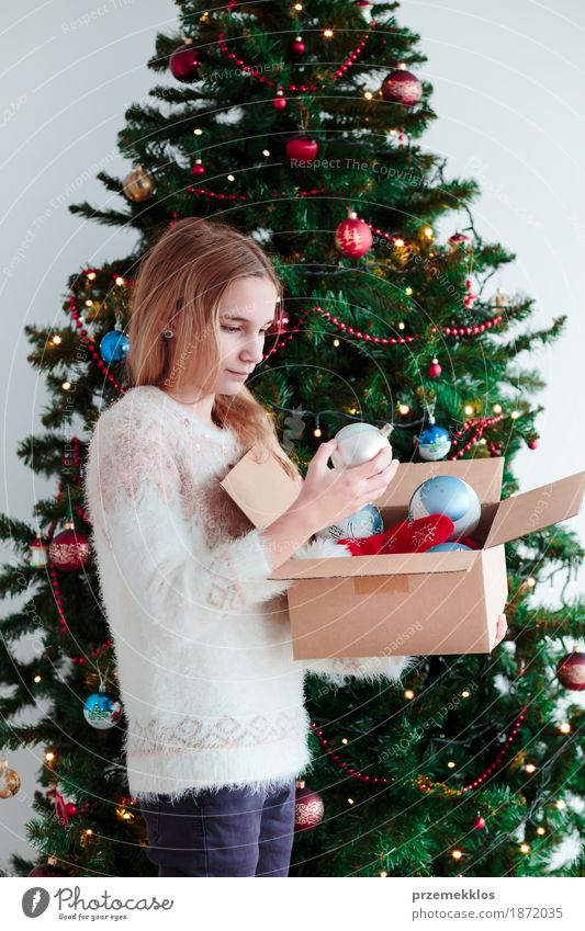 Young girl decorating Christmas tree at home Lifestyle Joy Decoration Feasts & Celebrations Christmas & Advent Human being Girl Youth (Young adults) 1