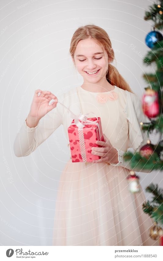 Happy girl unpacking Christmas gift standing behind a tree Lifestyle Feasts & Celebrations Christmas & Advent Child Human being Girl 1 8 - 13 years Infancy Tree