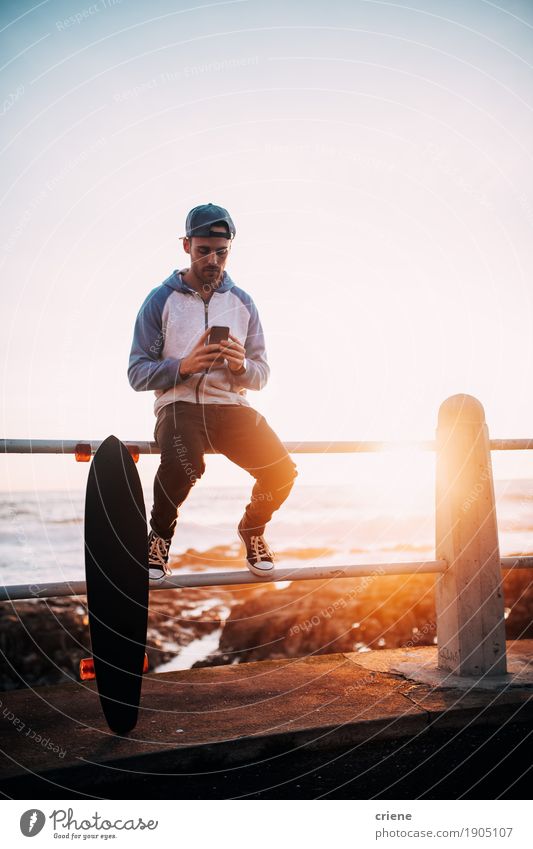 Young adult man sitting on railing browsing with smart phone Lifestyle To talk Telephone Cellphone PDA Technology Entertainment electronics Telecommunications