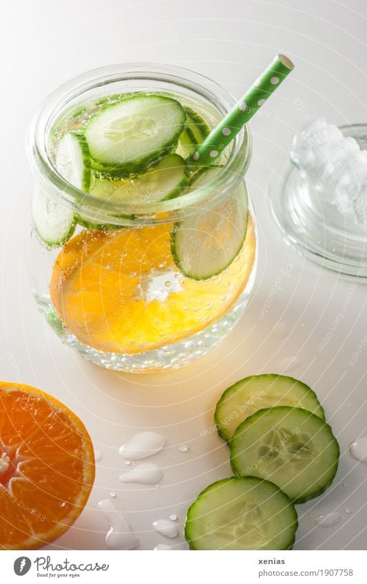 A glass of soft drink with tangerine, cucumber and straw on white background Beverage Cold drink Tangerine Fruit Slices of cucumber Drinking Drinking water