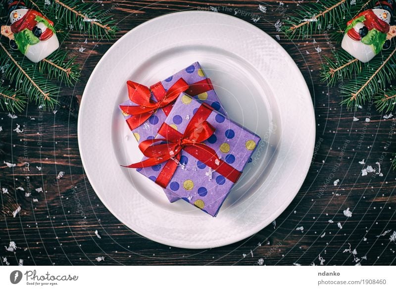 Two gift wrapped in paper with a red ribbon on a white plate Breakfast Lunch Dinner Crockery Plate Cutlery Winter Snow Decoration Table Restaurant