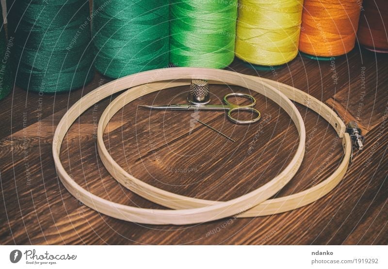colored thread in the coils with wooden hoops for embroidery Design Table Industry Craft (trade) Scissors Places Fashion Clothing Wood Brown Yellow Green Orange