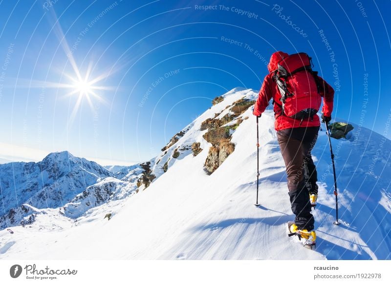 Mountaineer faces a climb at the top of a snowy peak. Vacation & Travel Adventure Expedition Winter Snow Hiking Sports Climbing Mountaineering Success