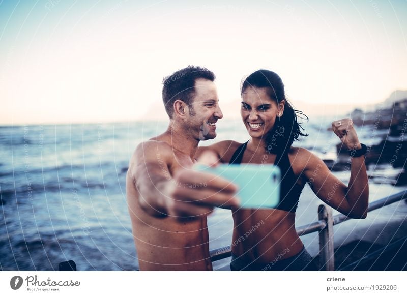 young athlete couple taking selfie with smartphone Lifestyle Joy Beach Ocean Waves Sports Telephone PDA Camera Young woman Youth (Young adults) Young man Couple