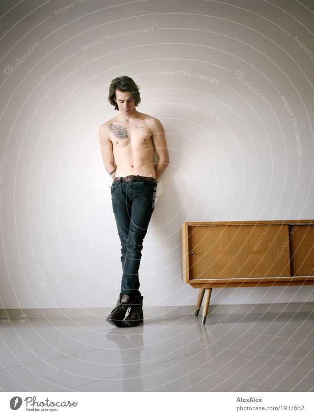 young man with tattoo leans bare-chested in a bright room next to a sideboard Flat (apartment) Furniture Young man Youth (Young adults) Naked 18 - 30 years