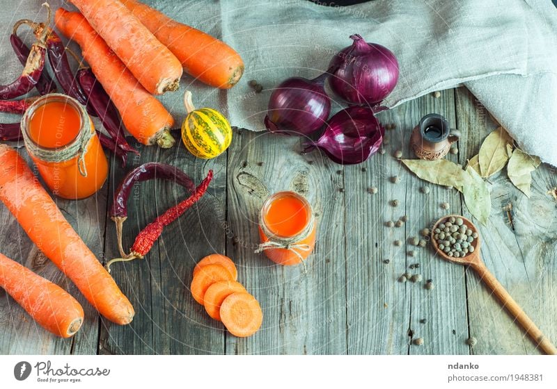 Fresh carrots and carrot juice in a glass container Vegetable Herbs and spices Vegetarian diet Diet Beverage Juice Glass Table Kitchen Nature Wood Old Eating