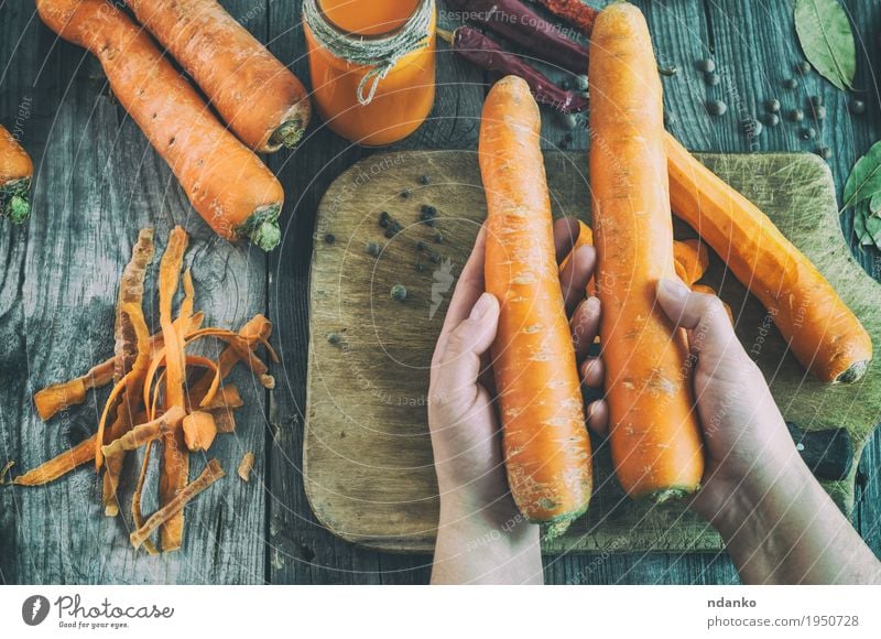 Two large ripe carrots lie in female hands Vegetable Herbs and spices Nutrition Eating Vegetarian diet Diet Beverage Juice Knives Body Table Woman Adults Skin